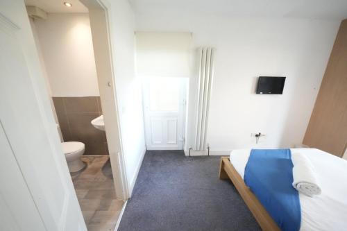 a bedroom with a bed and a bathroom with a toilet at Private on suites- Private Bathroom every room-1 Bus to Heathrow Airport in Harmondsworth