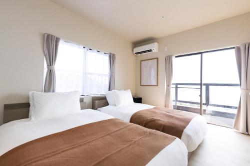 two beds in a room with two large windows at Vast Bleu IWAYA in Awaji