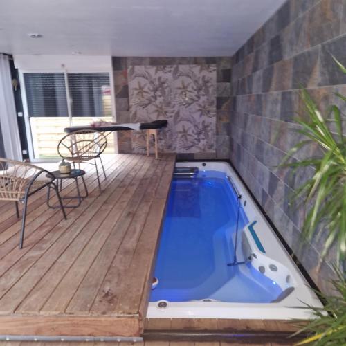 a hot tub on a wooden deck with a table at Escapade Romantique à Saint Omer-Espace Totalement Privatisé Avec Terrasse in Saint-Omer