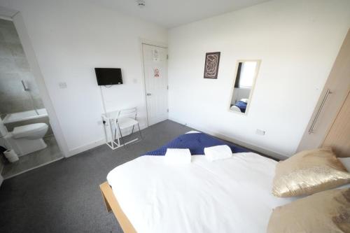 a white bedroom with a bed and a sink at Private on suites- Private Bathroom every room-1 Bus to Heathrow Airport in Harmondsworth