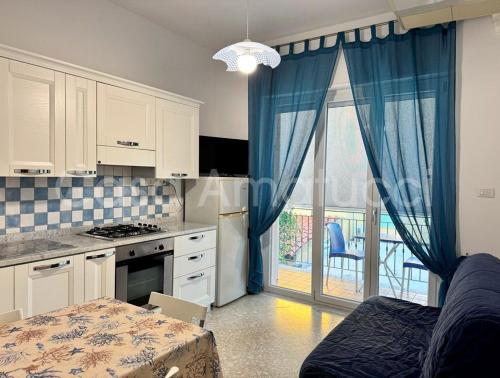 a kitchen with blue curtains and a table and a window at Casa Amatucci in Santa Maria di Castellabate