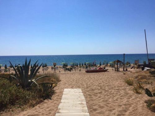a sandy beach with a wooden pathway and the ocean at Casa Amatucci in Santa Maria di Castellabate