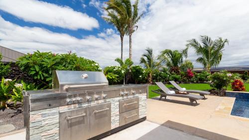 a outdoor kitchen with a grill and a pool at ISLAND SEABATICAL Restful 3BR Ainamalu Home with Private Pool in Waikoloa
