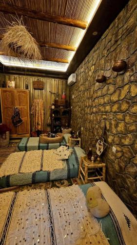 a room with three beds and a stone wall at Château Berbère Madame DELLAL in Taroudant