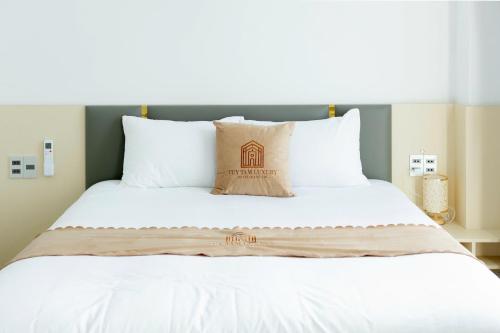 a large bed with white sheets and pillows at Tuỳ Tâm Luxury Hotel Quảng Trị in Ðông Hà