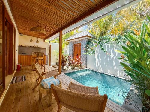a pool on a deck with chairs and a table at Muzeum Villas II Bingin in Bingin Beach