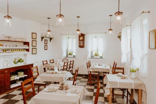 a restaurant with white tables and chairs and a fireplace at Kosbor Panzió in Magyarszombatfa