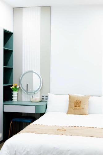a bedroom with a bed and a desk with a mirror at Tuỳ Tâm Luxury Hotel Quảng Trị in Ðông Hà