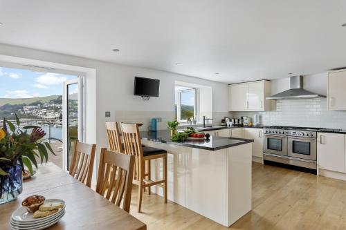 a kitchen with white cabinets and a table with chairs at Kittiwake - Outstanding River Views in Dartmouth
