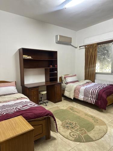 Un dormitorio con dos camas y un escritorio. en 3 Bedroom Family Apartment in Amman, en Amán