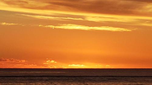an orange sky over the ocean with the sun setting at BoTree Abode in Flic-en-Flac