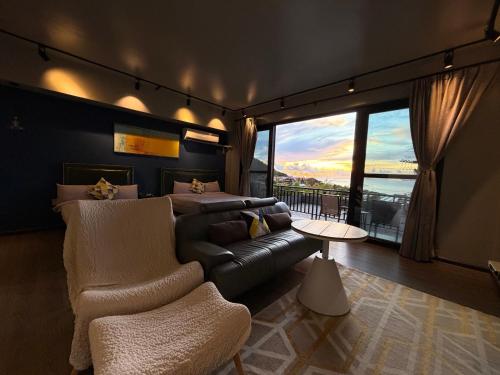 a bedroom with a bed and a couch and a window at Saipan Skyline Designers Hotel in Saipan