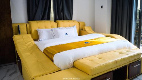 OtinibiにあるSkycity Hotel Ghの黄色いヘッドボードと黄色いソファが付いた大きなベッド