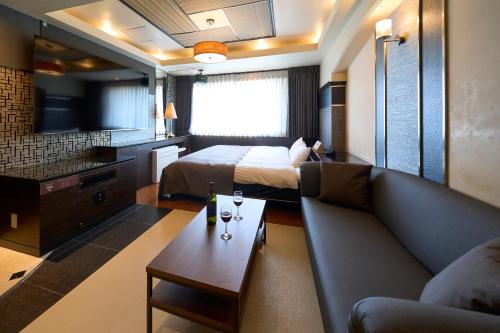 una camera d'albergo con divano, letto e TV di ホテル フェスタ 葉山 a Hayama