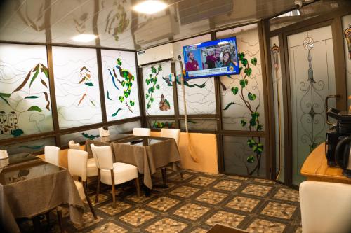 a dining room with tables and chairs and a tv on the wall at Hotel Old Rustaveli in Tbilisi City