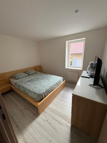 een slaapkamer met een bed en een bureau met een televisie bij Calme maison de campagne in Cressin-Rochefort