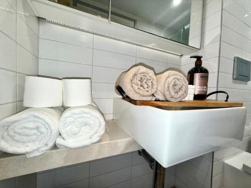 a bathroom with towels on a shelf and a sink at The Padbury Suites-Premium City Apartment in Karratha