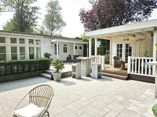 a patio with a table and chairs and a house at Chalet Kieftveen with hot tub for four Person in Voorthuizen