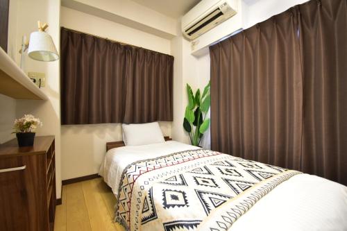 a bedroom with a bed and a dresser and a window at Alphabed広島平和大通り in Hiroshima