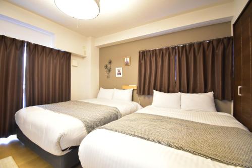 a hotel room with two beds and curtains at Alphabed広島平和大通り in Hiroshima