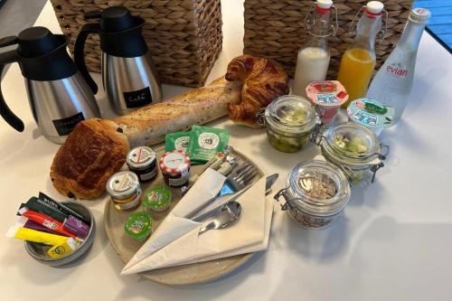 uma mesa coberta com pão, café e garrafas de leite em Clos du Riez - Suites & SPA em La Gorgue