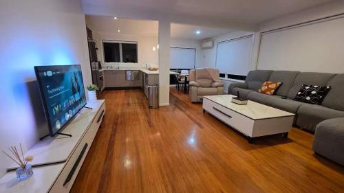 a living room with a couch and a flat screen tv at Northshore Central Cosy & Comfortable 3BR Home in Auckland