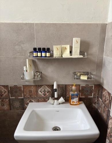 lavabo blanco en un baño con estanterías en Musawir's Stay, en Hyderabad