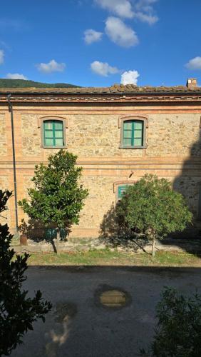 a brick building with two windows and two trees at Castello di Vecchienna in Monterotondo