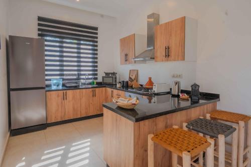 a kitchen with wooden cabinets and stainless steel appliances at Villa La Rose Bleue - Résidence Hôtelière avec Piscine - Essaouira in Essaouira
