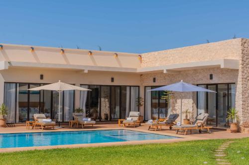 a villa with a swimming pool and umbrellas at Villa La Rose Bleue - Résidence Hôtelière avec Piscine - Essaouira in Essaouira