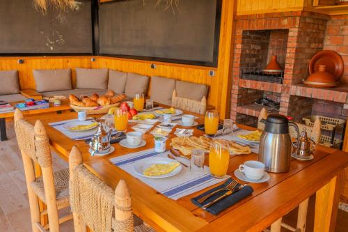 a wooden table with food and orange juice on it at Villa La Rose Bleue - Résidence Hôtelière avec Piscine - Essaouira in Essaouira