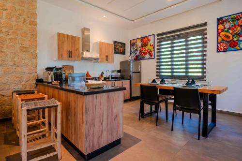 a kitchen with a counter and a table with chairs at Villa La Rose Bleue - Résidence Hôtelière avec Piscine - Essaouira in Essaouira