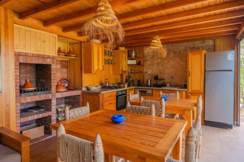 a kitchen with a wooden table and a white refrigerator at Villa La Rose Bleue - Résidence Hôtelière avec Piscine - Essaouira in Essaouira