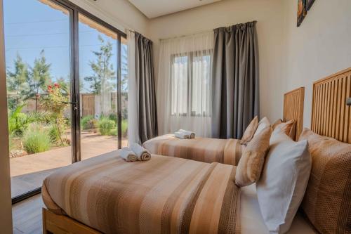 two beds in a bedroom with a large window at Villa La Rose Bleue - Résidence Hôtelière avec Piscine - Essaouira in Essaouira
