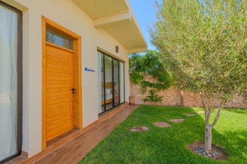 a house with a wooden door and a tree in the yard at Villa La Rose Bleue - Résidence Hôtelière avec Piscine - Essaouira in Essaouira