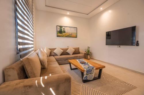 a living room with a couch and a tv at Villa La Rose Bleue - Résidence Hôtelière avec Piscine - Essaouira in Essaouira