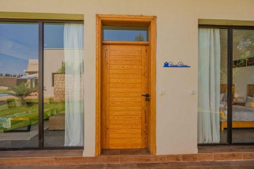 a wooden door in a house with windows at Villa La Rose Bleue - Résidence Hôtelière avec Piscine - Essaouira in Essaouira