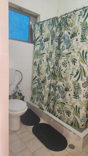 une salle de bain avec toilettes et rideau de douche dans l'établissement Meeting Point Praia-QC Beachwalk, also in Tarrafal & Fogo-NO CASH ACCEPTED, à Praia