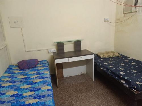 a room with a desk and a bed and a desk and a bed at Kedwin Dormitory in Mumbai