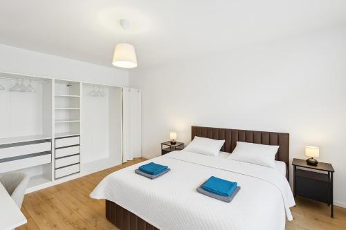 - une chambre avec un lit blanc et des serviettes bleues dans l'établissement Erholsame Wohnung mit Balkon und Einbauküche im Herzen Leipzigs, à Leipzig