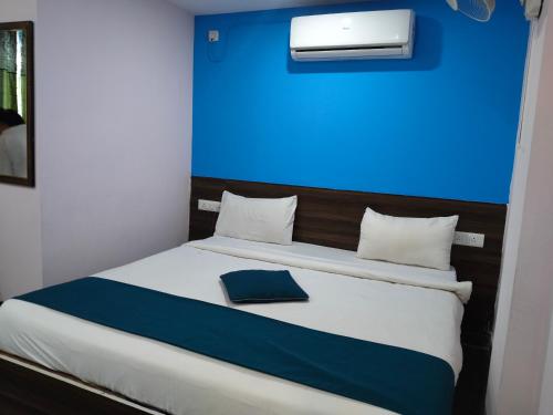 a bed in a room with a blue wall at Hotel grand meridian in in Bengaluru
