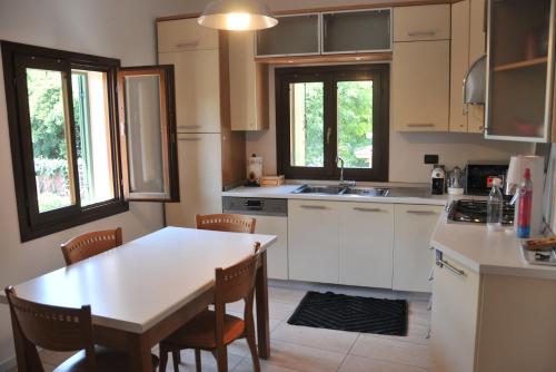 a kitchen with white cabinets and a table and chairs at Casa Sant Anna in Pordenone
