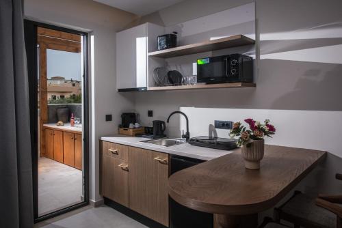 a kitchen with a sink and a table with a vase of flowers at VAYA Suites by Omilos Hotels in Amoudara Herakliou