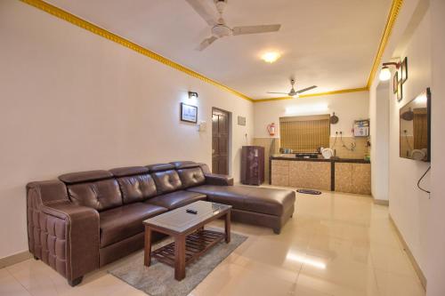 a living room with a brown leather couch and a table at Amazing Pool View 2BHK Candolim Goa Apartment in Candolim