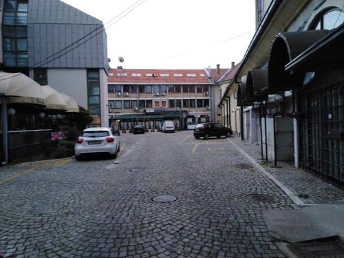 a city street with cars parked on the street at Hotel Grand Hedonist in Pančevo