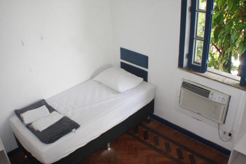 a small bed in a room with a window at Farfalla Guest House in Rio de Janeiro