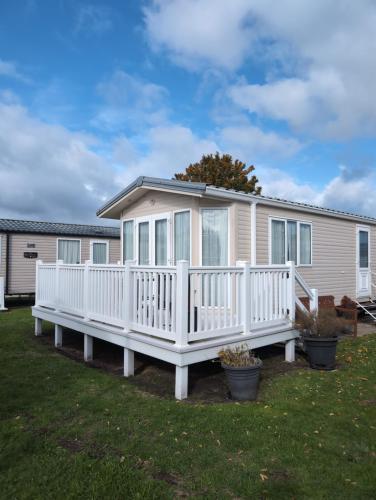 a house with a white railing and a porch at Sea Shore Chalet - Rockley Park in Lytchett Minster