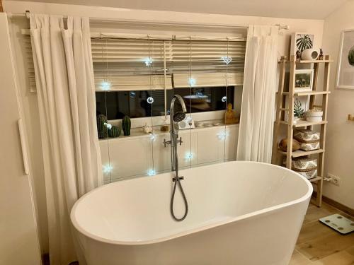 Una bañera blanca en una habitación con ventana. en The Wurmstein House - Contemporary Mountain Home, en Bad Goisern