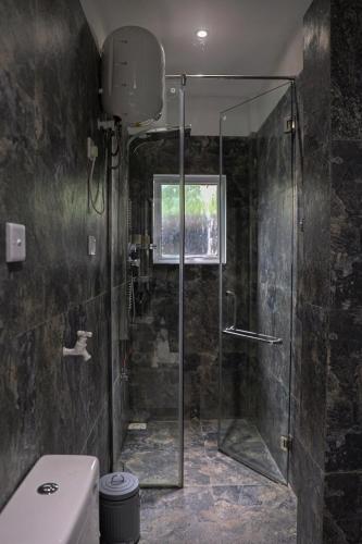 a bathroom with a glass shower with a toilet at K's Cove in Kandy