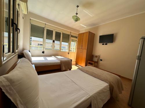 a hotel room with two beds and a tv at Hotel Kudhesi in Vlorë